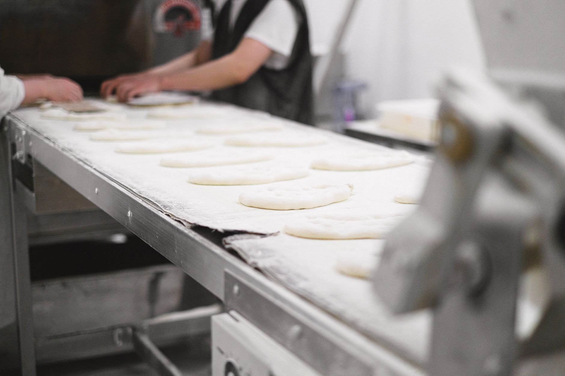Bakery workers shaping dough on a production line — industrial food manufacturing